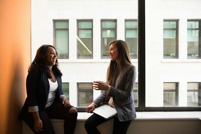 Two women in conversation by a window