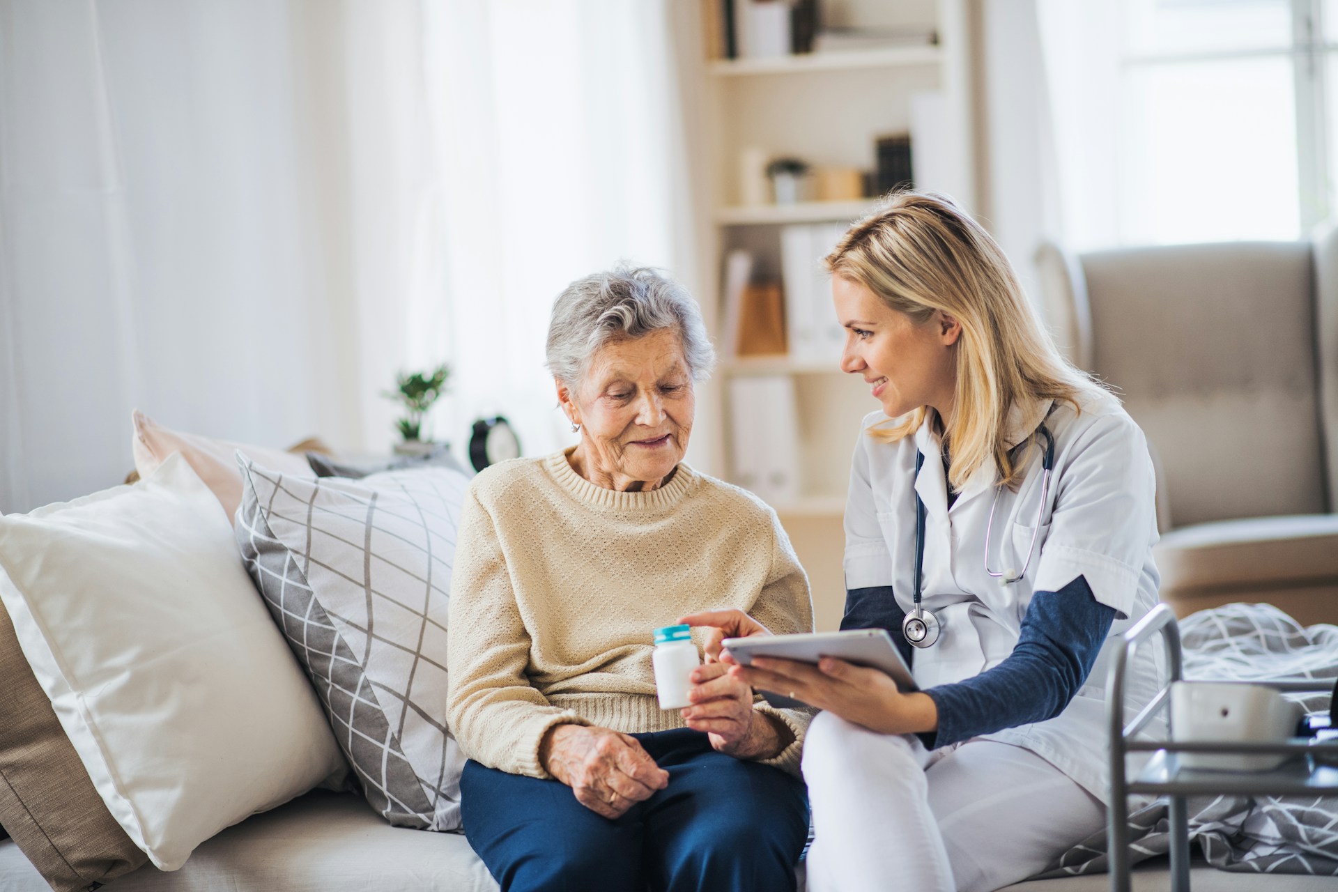 A social care worker using a tablet to assess an older patient